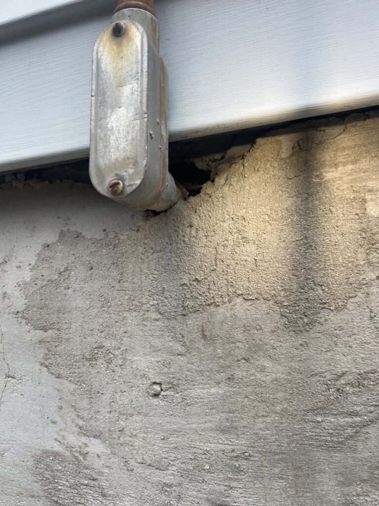 Residential rodent exclusion 2 Open gap where an electrical conduit fitting meets siding and foundation on a worcester county home, a mouse entry point